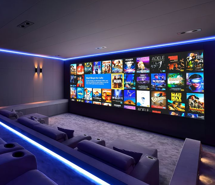 Dedicated home cinema room with full wall projection screen and tiered luxury seating